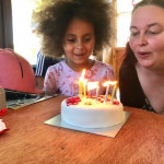 Girl with afro blowing out birthday candles in County Antrim