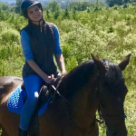 Woman with blue clothes sitting on dark brown horse in County Antrim