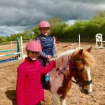 2 kids smiling while riding a horse in County Antrim